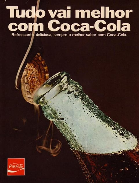 Esta é uma imagem que ilustra um anúncio publicitario da Coca-Cola, há nele uma garafa de vidro sendo destampada e a um texto que lembra o público da qualidade do refrigerante: "Tudo vai melhor com Coca-Cola"
